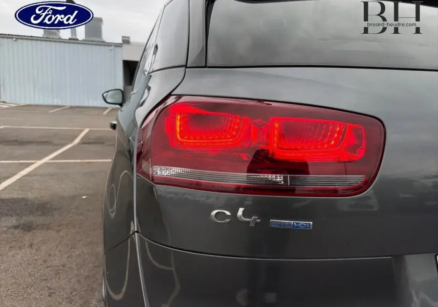 Gros plan sur le feu arrière droit d'une Citroën C4 Picasso gris Shark avec logo C4 et badge BlueHDi visible.