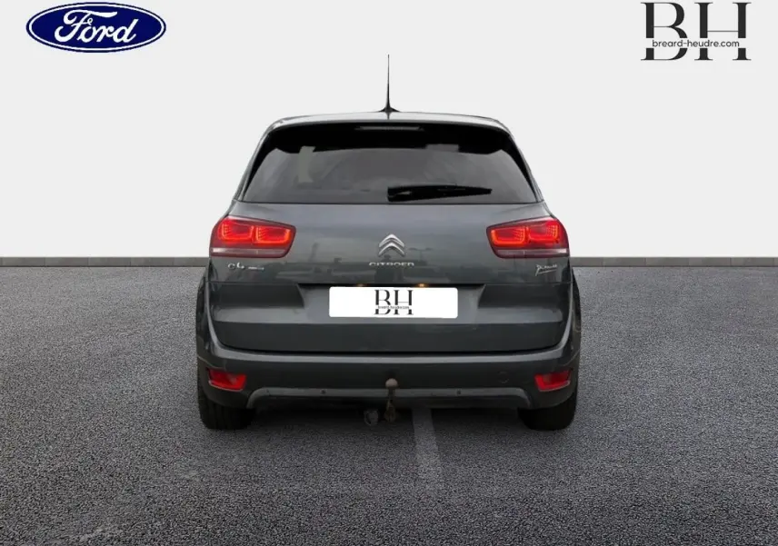 Vue arrière d'une Citroën C4 Picasso gris Shark avec feux allumés et attelage visible.