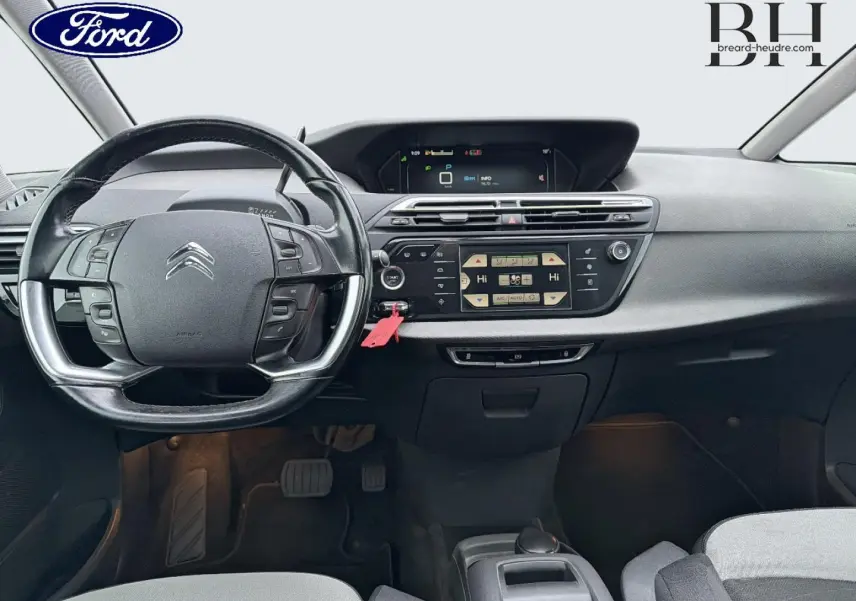 Vue intérieure frontale du tableau de bord et volant noir d'une Citroën C4 Picasso gris Shark de 2016.