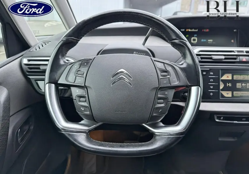 Gros plan sur le volant cuir multifonction Citroën C4 Picasso gris, avec tableau de bord et écran tactile en arrière-plan.
