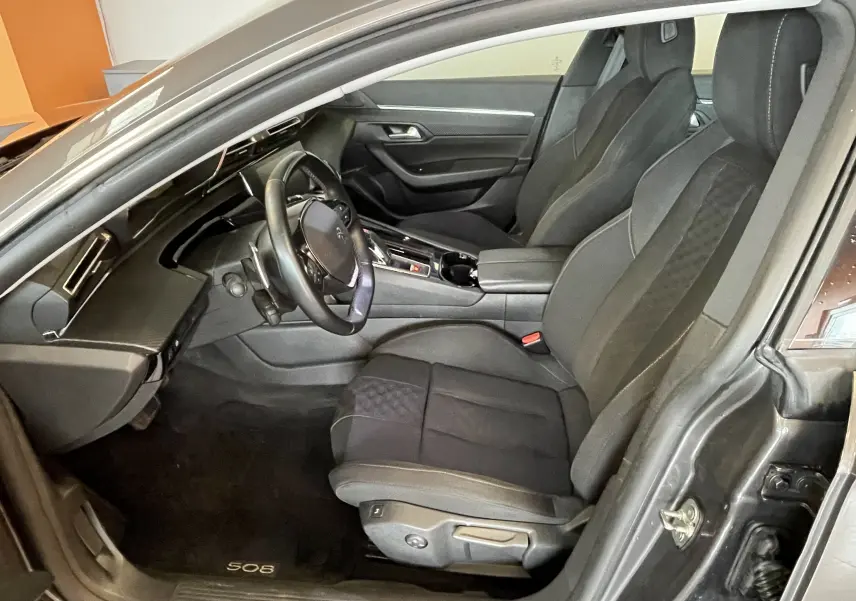 Intérieur avant droit de la Peugeot 508 gris platinium, sièges noirs avec surpiqûres et tableau de bord moderne.