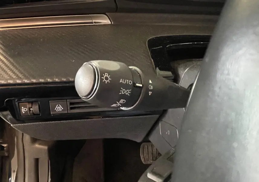 Gros plan sur la commande d'éclairage automatique à gauche du volant dans l'habitacle du Peugeot 508 gris platinium.