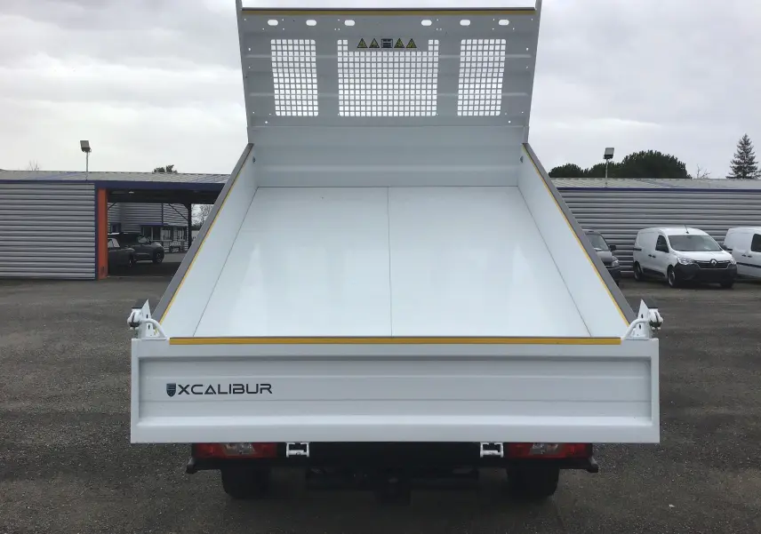 Vue arrière frontale d'une benne blanche Xcalibur sur un Ford Transit Chassis Cabine 2024, plateau relevé.