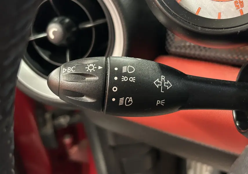 Gros plan sur le bouton Start/Stop et la clé insérée dans une MINI Cabriolet Cooper S rouge, tableau de bord en cuir rouge.