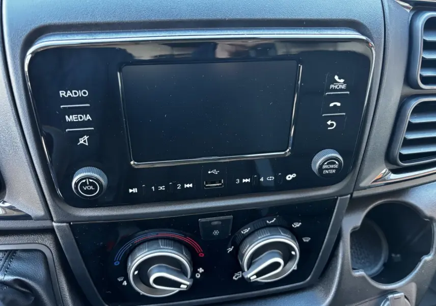 Tableau de bord du Peugeot Boxer Fourgon 2025 montrant l'écran tactile et les commandes de climatisation noires.