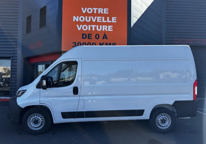 Fourgon Peugeot Boxer blanc vu de profil côté gauche, avec cloison pleine et jantes acier grises.