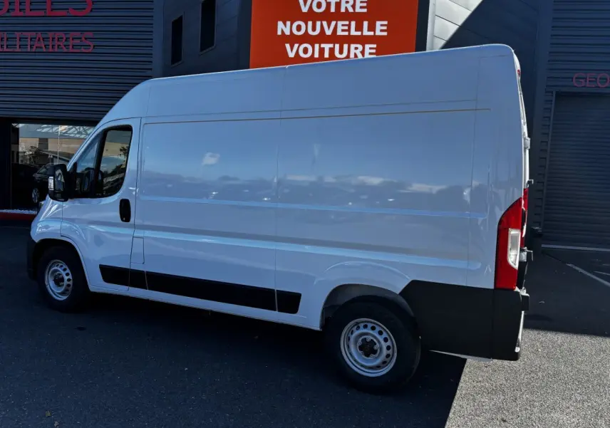 Vue latérale droite d'un utilitaire Peugeot Boxer Fourgon blanc, avec cloison pleine et jantes acier simples.