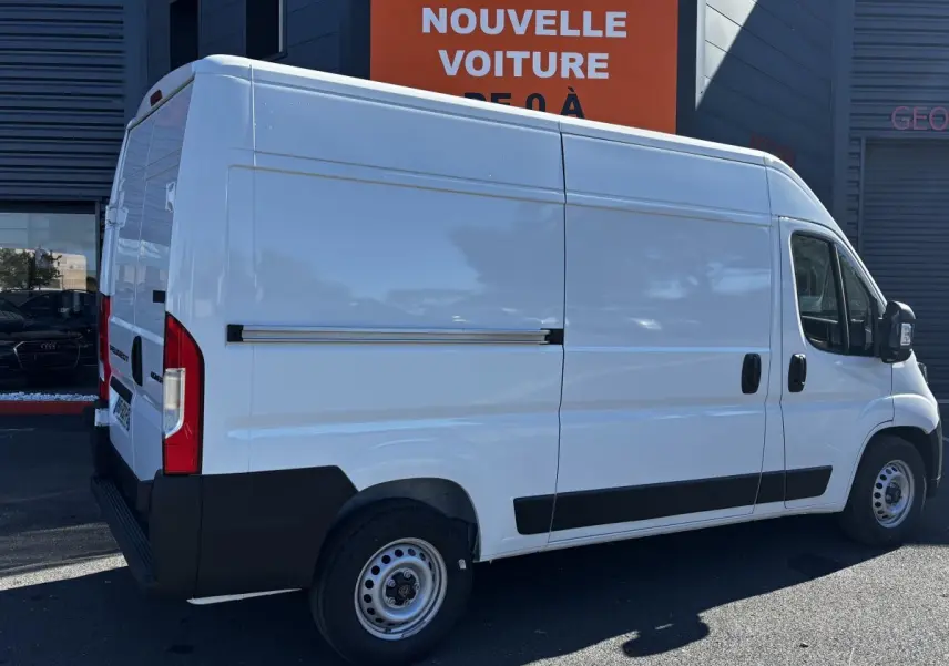Vue 3/4 arrière droite d'un Peugeot Boxer Fourgon blanc avec carrosserie haute et bas de caisse noir.