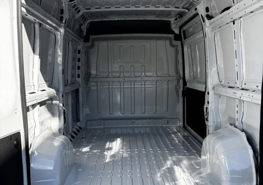 Intérieur du coffre blanc du Peugeot Boxer Fourgon L2H2 2025, vue arrière ouverte montrant l'espace de chargement vide et métallique.