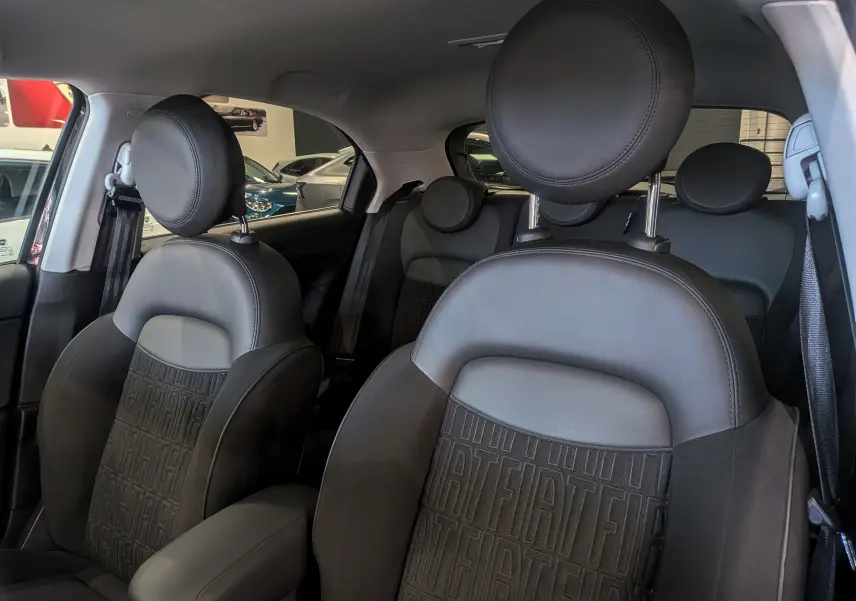 Vue intérieure rapprochée des sièges avant en microfibre noire avec logo FIAT embossé sur une Fiat 500X 2024.