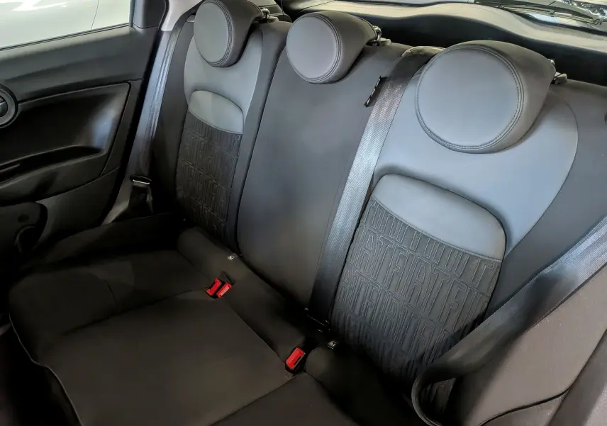 Vue intérieure des sièges arrière noirs du Fiat 500X 2024 avec appuie-têtes ronds et motifs FIAT sur les dossiers.