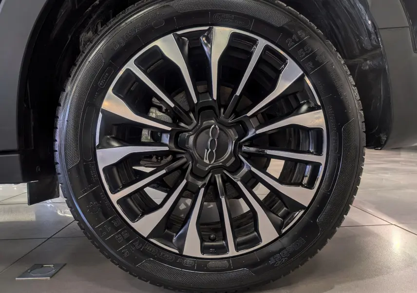 Gros plan sur la jante avant droite noire et argentée du FIAT 500X 2024 en Noir Cinéma.