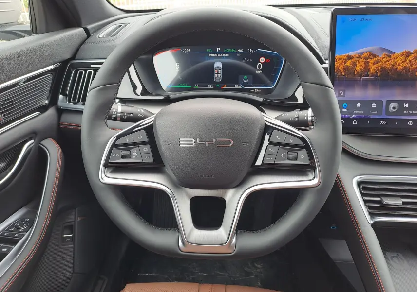 Vue intérieure centrée sur le volant noir et gris du BYD SEAL U 2025 avec tableau de bord numérique et écran tactile.