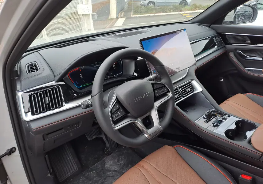 Vue intérieure côté conducteur du BYD SEAL U 2025, tableau de bord noir, sièges marron et écran tactile central.