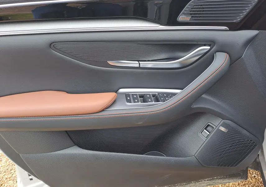 Vue détaillée de la porte avant gauche du BYD SEAL U 2025 en BOUNDLESS CLOUD, avec garniture cuir marron et haut-parleur Infinity.