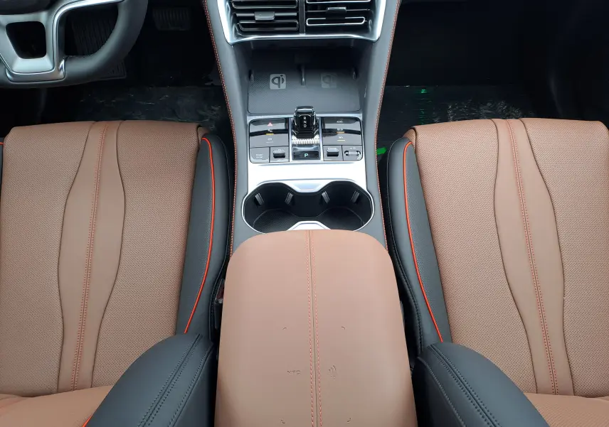 Vue intérieure centrée sur la console centrale et les sièges avant en similicuir marron avec surpiqûres rouges du BYD SEAL U.