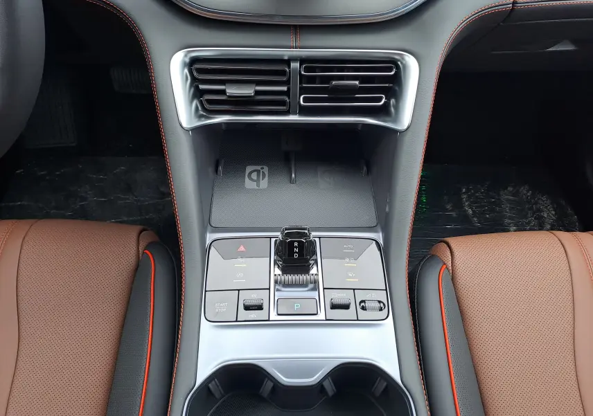 Vue plongeante sur la console centrale argentée du BYD SEAL U avec sièges marron et surpiqûres orange visibles.