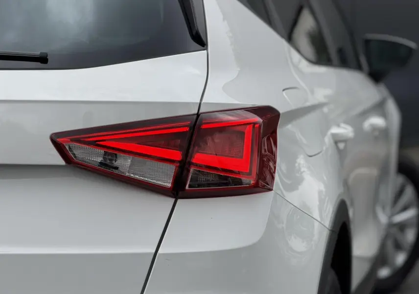 Gros plan sur le feu arrière droit d'un SEAT Arona blanc, mettant en valeur la ligne anguleuse et la carrosserie brillante.