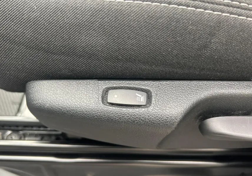 Gros plan sur le bouton de siège chauffant noir intégré à la garniture intérieure d’un Nissan Primastar gris Highland.
