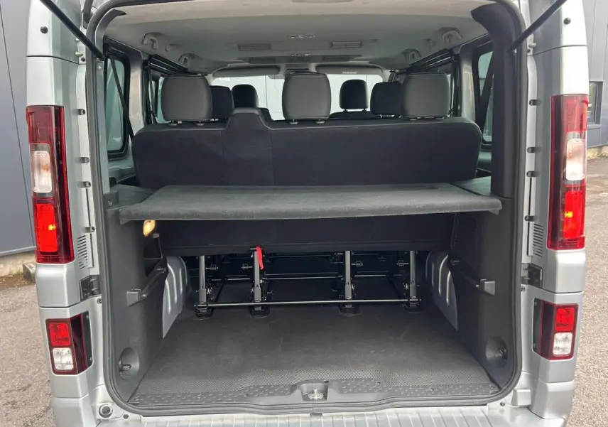 Vue arrière ouverte du Nissan Primastar gris Highland 2025, montrant l'espace de chargement et les sièges arrière.