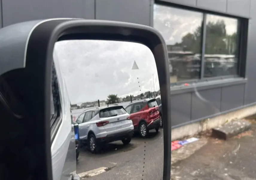 Rétroviseur extérieur droit d’un Nissan Primastar gris Highland, avec affichage d’alerte d’angle mort visible.
