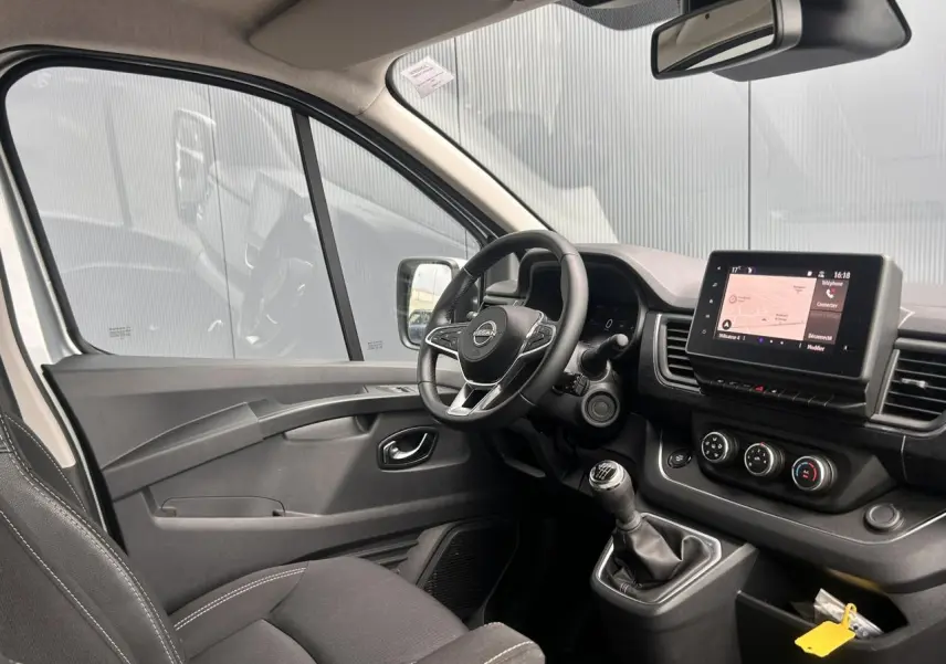 Vue intérieure côté conducteur du Nissan Primastar 2025 avec tableau de bord noir et écran tactile central.