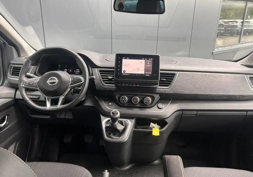 Vue intérieure frontale du tableau de bord du Nissan Primastar gris avec volant multifonction et écran tactile central.
