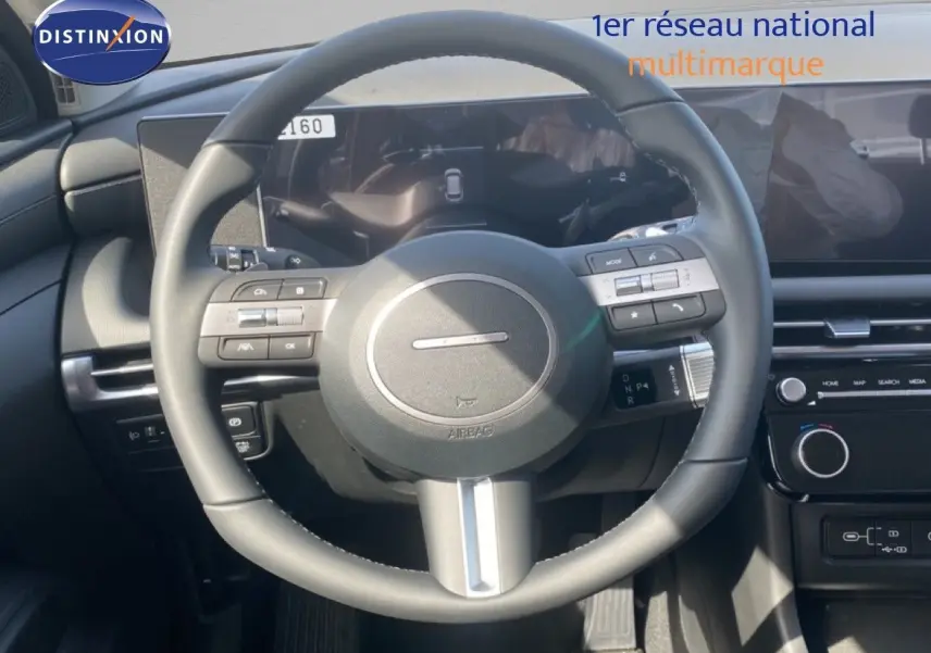Vue centrée sur le volant cuir multifonction du Hyundai Tucson 2026 gris Ecotronic, avec tableau de bord digital et écran tactile.