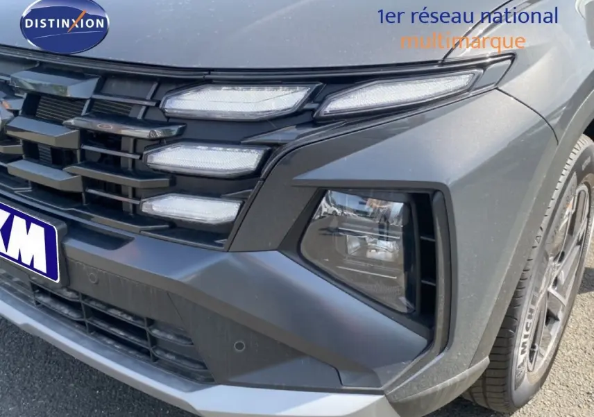 Gros plan sur l'avant droit du Hyundai Tucson gris Ecotronic Metal, mettant en valeur la calandre et les phares LED.