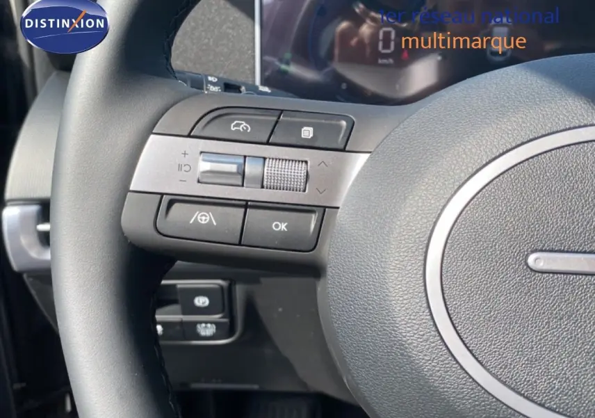 Gros plan sur le volant multifonction du Hyundai Tucson 2026 avec commandes intégrées et tableau de bord numérique flou en arrière-plan.
