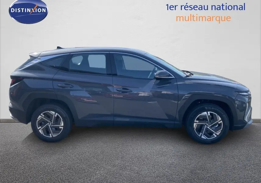 Vue de profil côté gauche du Hyundai Tucson gris Ecotronic Metal 2026 avec jantes alliage bicolores et lignes anguleuses.