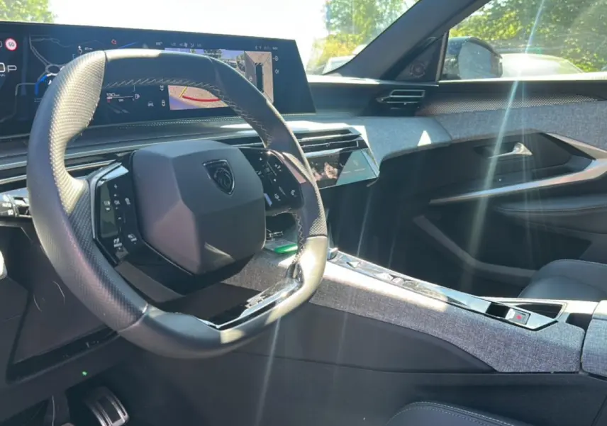 Vue intérieure côté conducteur du Peugeot 3008 gris 2025, volant cuir multifonction et écran tactile large en arrière-plan.