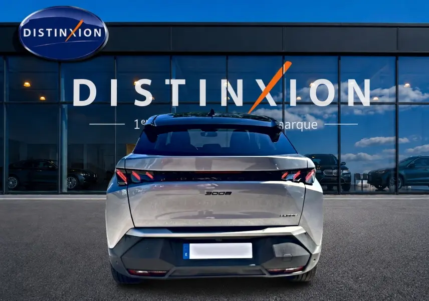 Vue arrière d'un Peugeot 3008 gris 2025 avec feux LED distinctifs et becquet arrière, devant une vitrine Distinxion.