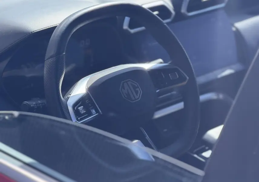 Gros plan sur le volant en cuir noir du MG ZS 1.5 Hybrid+ 197 Luxury avec tableau de bord et écran tactile visibles.
