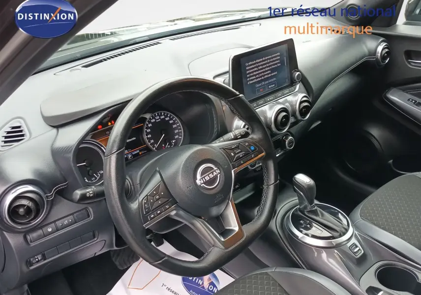 Vue intérieure côté conducteur du Nissan Juke Hybrid 2024 noir métal, avec tableau de bord et écran tactile central.