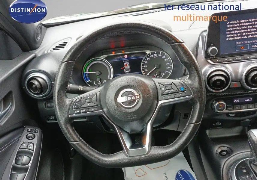 Vue intérieure centrée sur le volant cuir noir du Nissan Juke Hybrid 2024 avec tableau de bord et écran tactile.