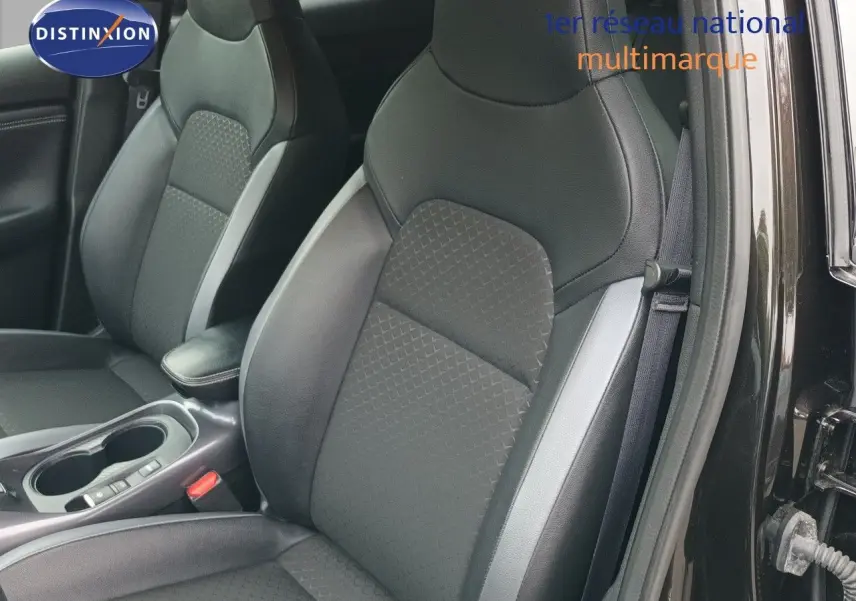 Vue intérieure sur les sièges avant en tissu noir et cuir d’un Nissan Juke Hybrid 2024, porte côté droit ouverte.