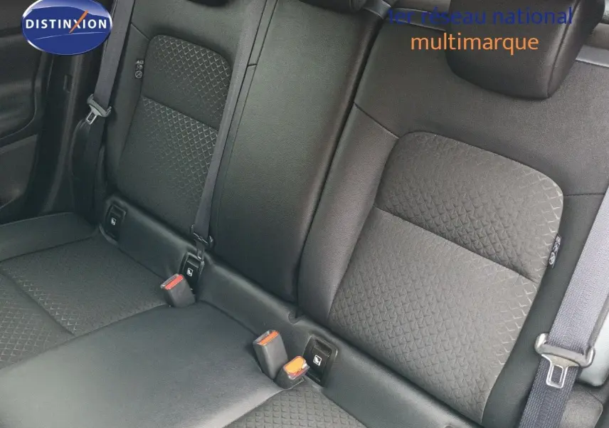 Vue rapprochée des sièges arrière noirs en tissu texturé du Nissan Juke Hybrid 2024, avec ceintures de sécurité visibles.