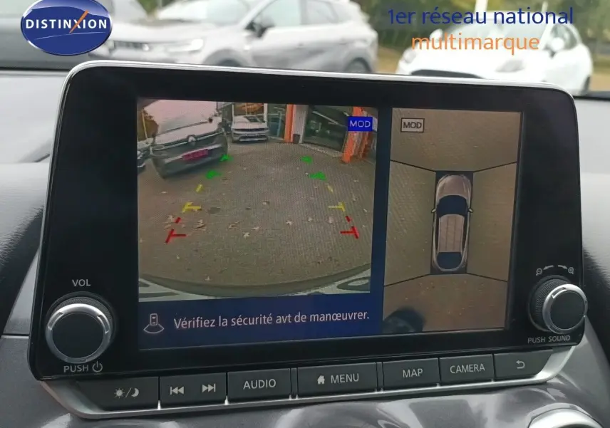 Écran multimédia montrant la caméra de recul et vue 360° du Nissan Juke noir métal, intérieur avec commandes visibles.