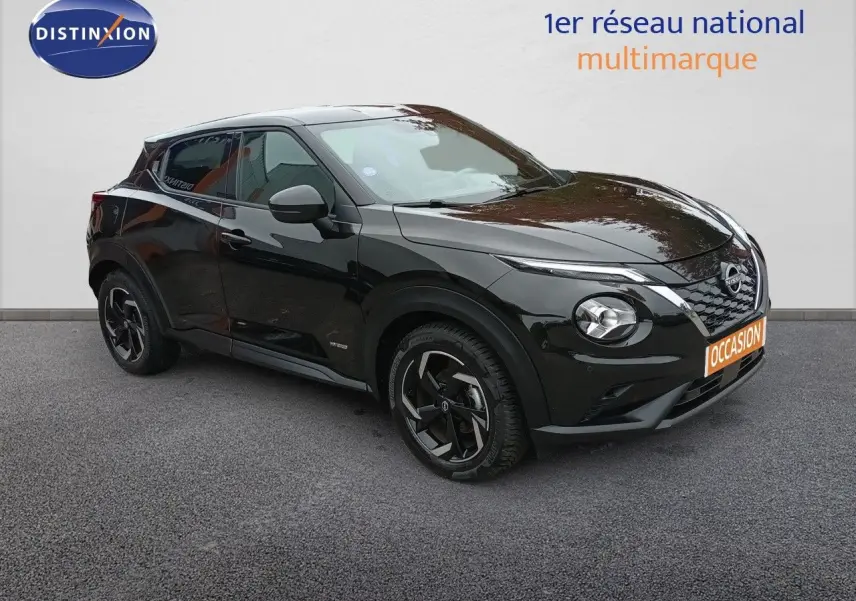 Nissan Juke Hybrid noir métal en 3/4 avant droit, avec jantes noires et calandre distinctive V-Motion.