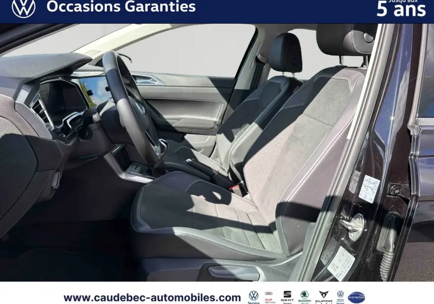 Vue intérieure côté conducteur de la Volkswagen Polo noire intense nacrée, montrant sièges et tableau de bord modernes.