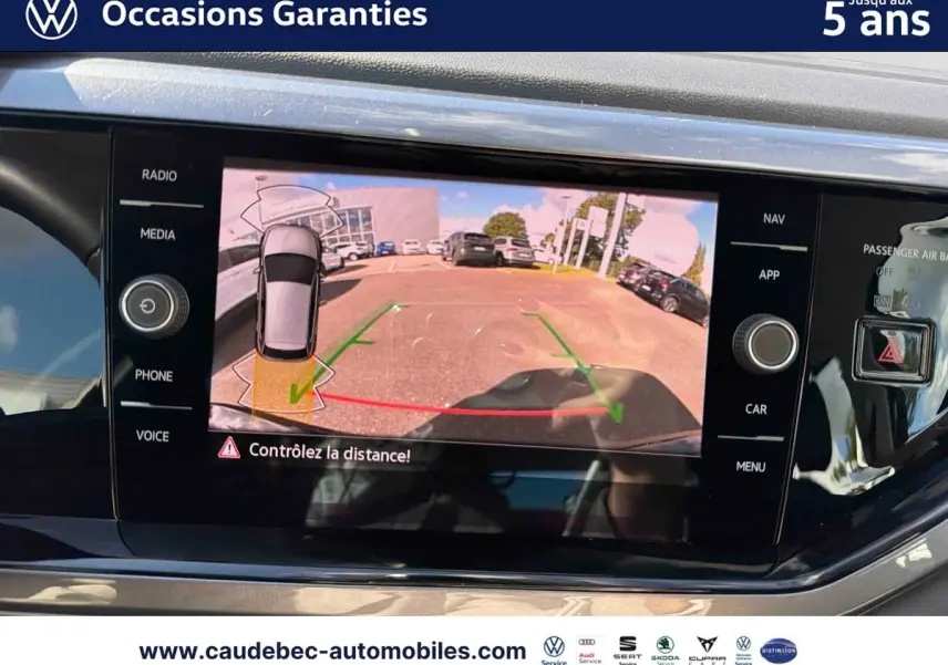 Écran tactile intérieur montrant la caméra de recul d'une Volkswagen Polo noire intense nacrée en stationnement.