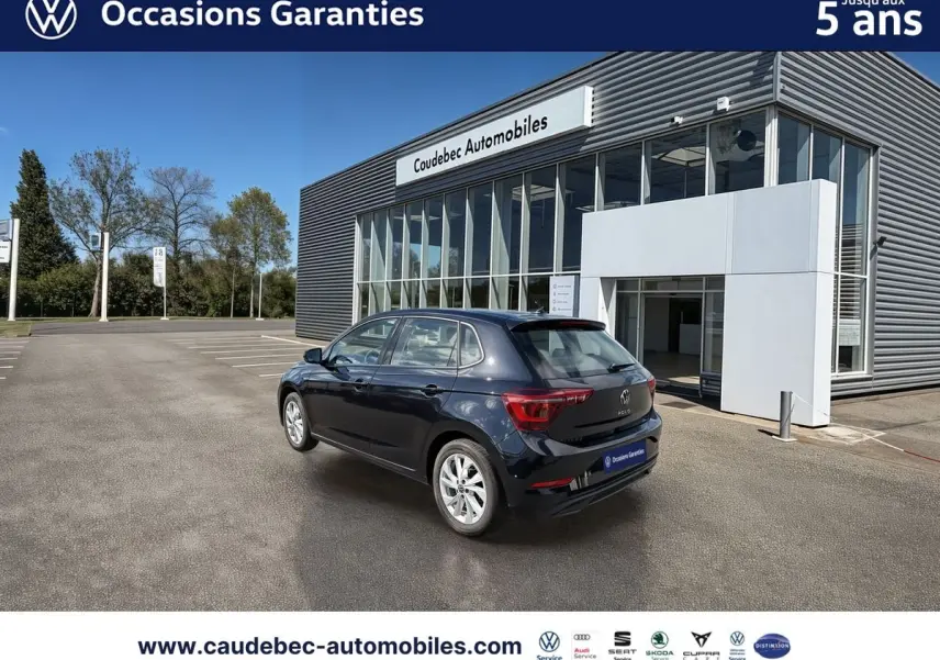 Vue 3/4 arrière droite d'une Volkswagen Polo noire intense nacrée avec jantes alliage Palermo 16 pouces, stationnée devant un bâtiment.