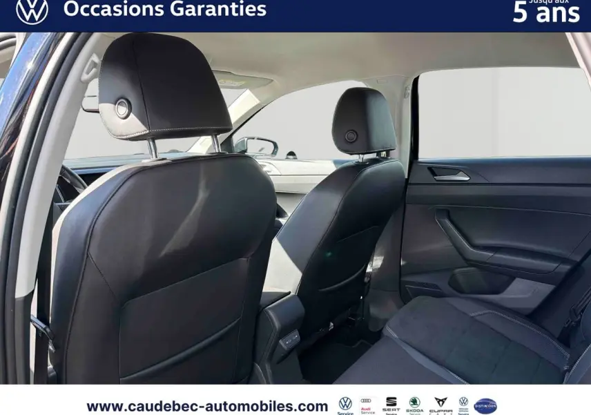 Vue intérieure arrière montrant les sièges avant en cuir noir et la banquette arrière tissu foncé d'une Volkswagen Polo 2025.