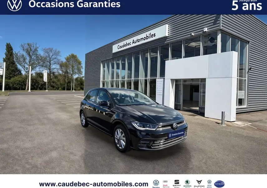 Volkswagen Polo noir intense nacré vue 3/4 avant droit, garée devant un bâtiment moderne de concession.