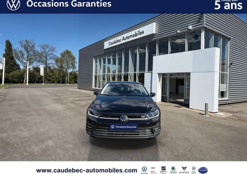 Volkswagen Polo noir intense nacré vue de face devant un bâtiment moderne de concession automobile.
