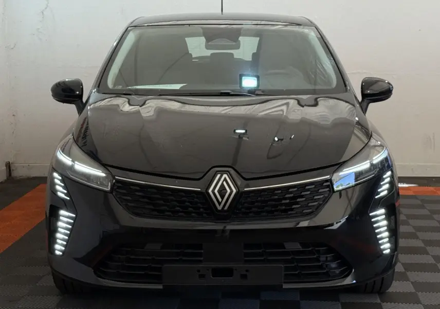 Vue frontale d'une Renault Clio noire 2025 avec feux LED verticaux et calandre au logo central lumineux.