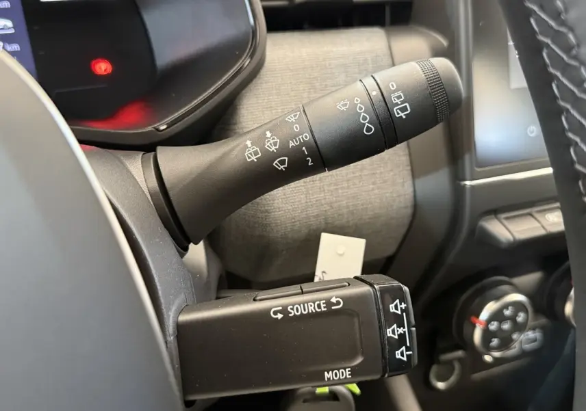 Gros plan sur les commandes de volant de la Renault Clio 2025, montrant les leviers de réglage et d'essuie-glace.