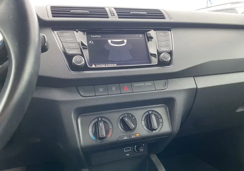 Vue intérieure centrée sur la console centrale d'une Skoda Fabia gris argent avec écran multifonction et commandes de climatisation manuelle.
