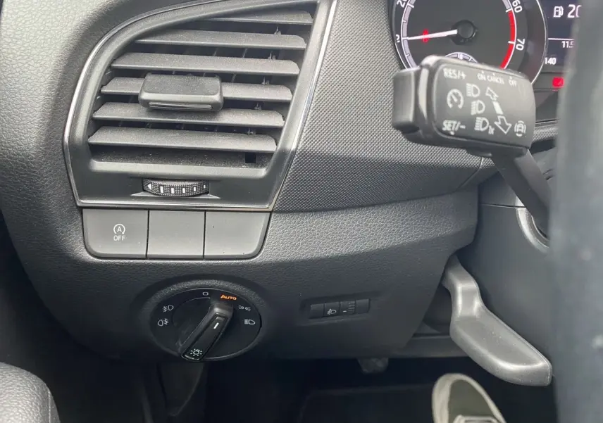 Vue rapprochée du tableau de bord côté gauche d'une Skoda Fabia gris argent, avec commandes d'éclairage et régulateur de vitesse.